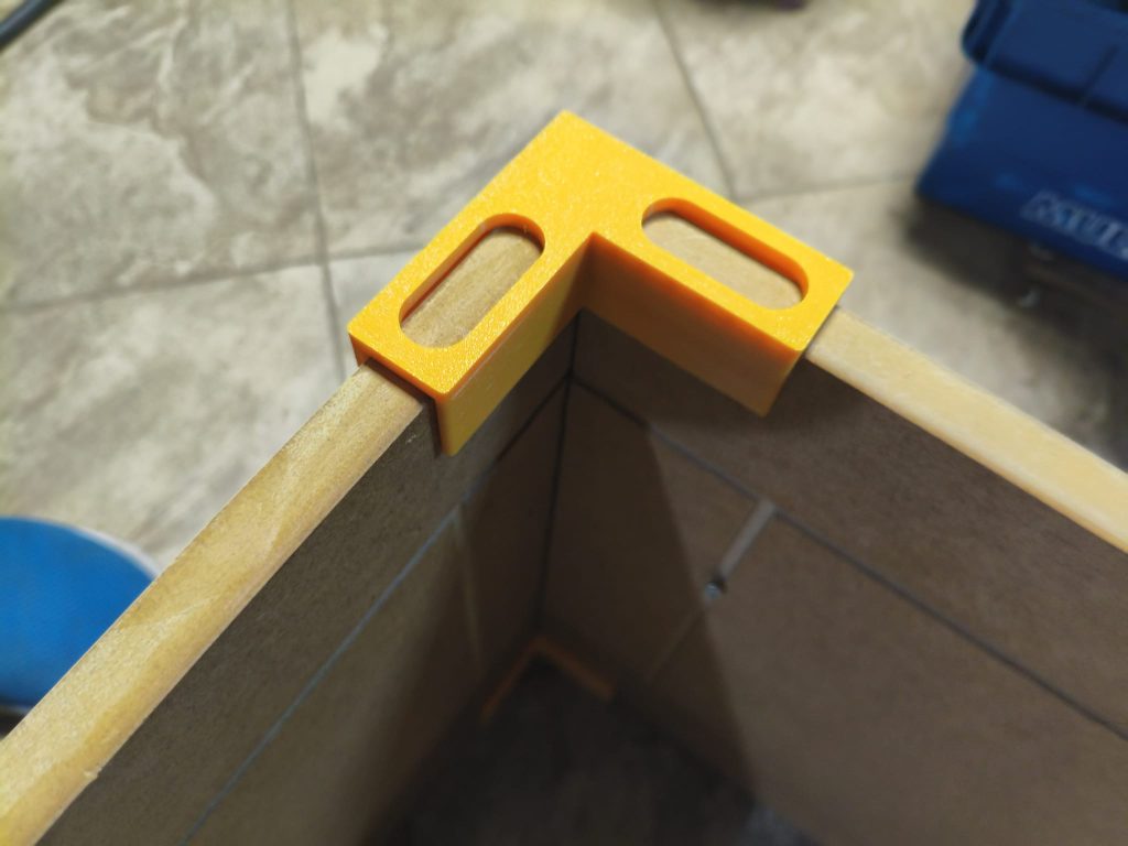 Żółte kąty meblowe z rowkami nasuwanymi na krawędzie płyty, wydruk 3D z PETG