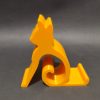 Żółta podstawka pod telefon w kształcie sylwetki siedzącego kota, wydruk 3D z PETG Żółta podstawka pod telefon w kształcie sylwetki siedzącego kota, wydruk 3D z PETG