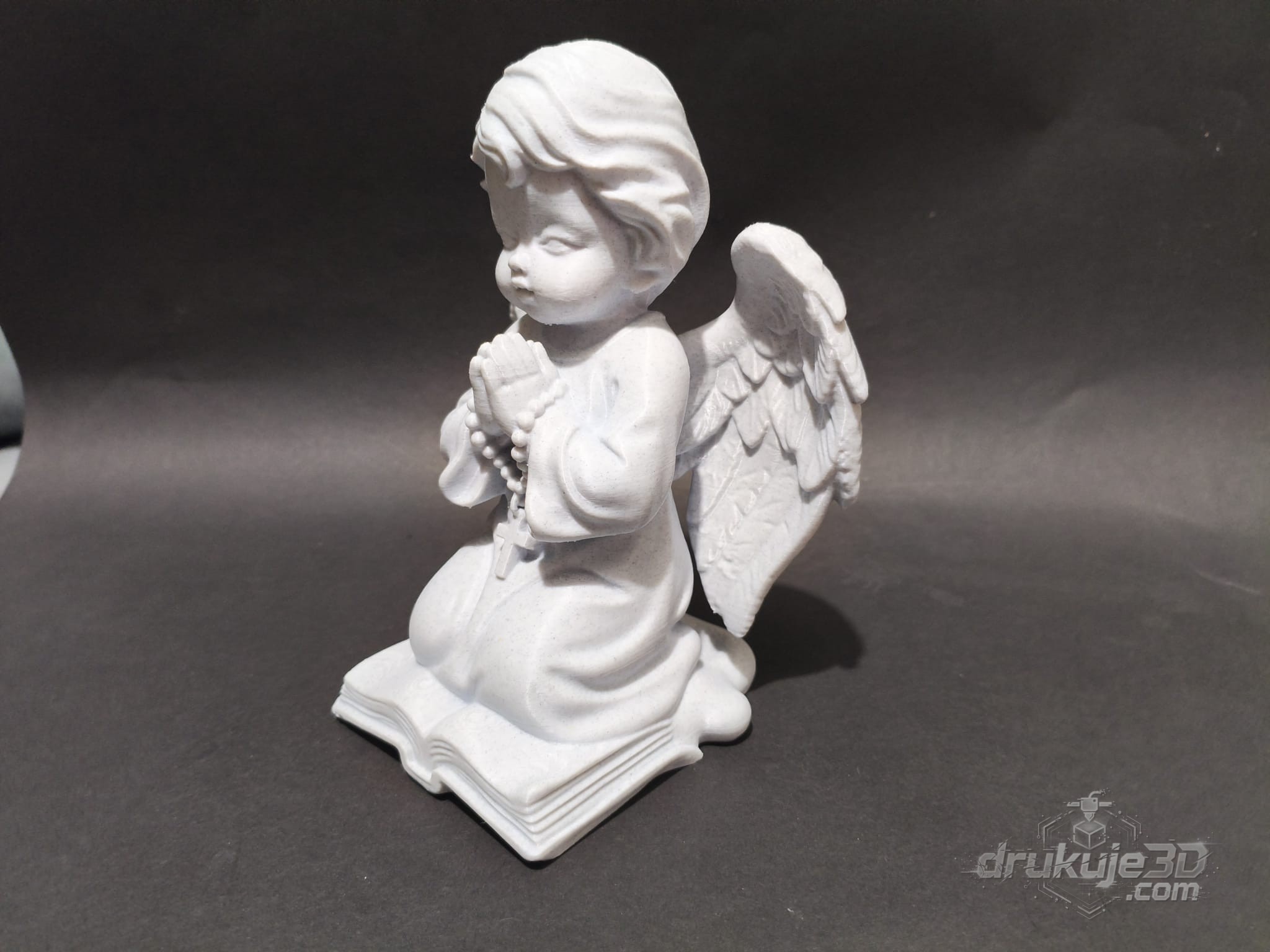Klęcząca figurka aniołka na grób z druku 3D, 20 cm, z różańcem w złożonych dłoniach, klęcząca na otwartej księdze, kolor marmurowy