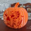 Pomarańczowa dynia z druku 3D o szerokości 24 cm, z ażurową twarzą wypełnioną pajęczynami, nietoperzami i gwiazdkami