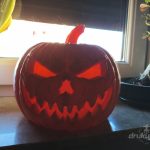 Straszna dynia z druku 3D o szerokości 24 cm, z rzeźbioną demoniczną twarzą i kłami, podświetlona od środka na czerwono